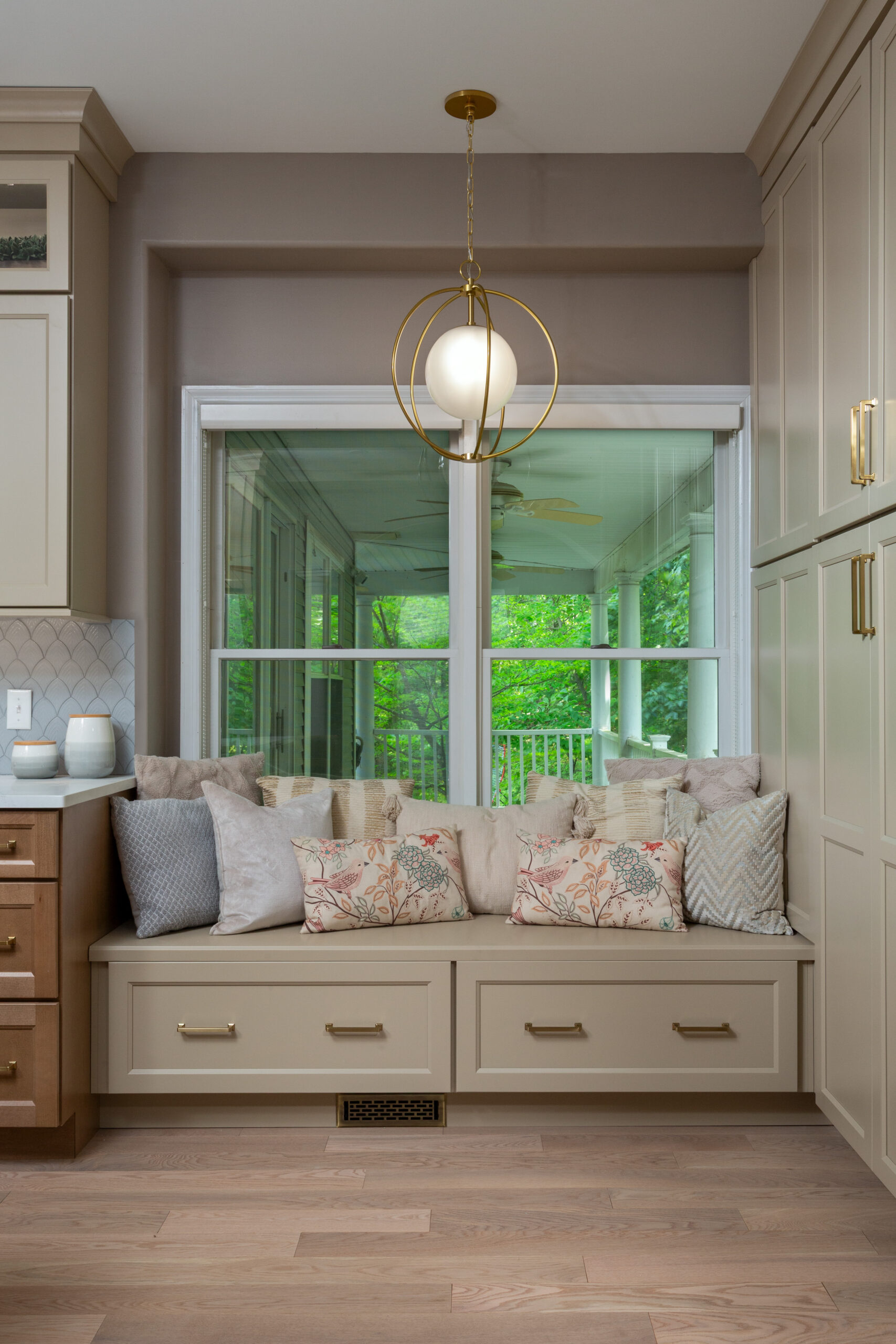 Built-in window bench with storage drawers and brass hardware in custom kitchen remodel.